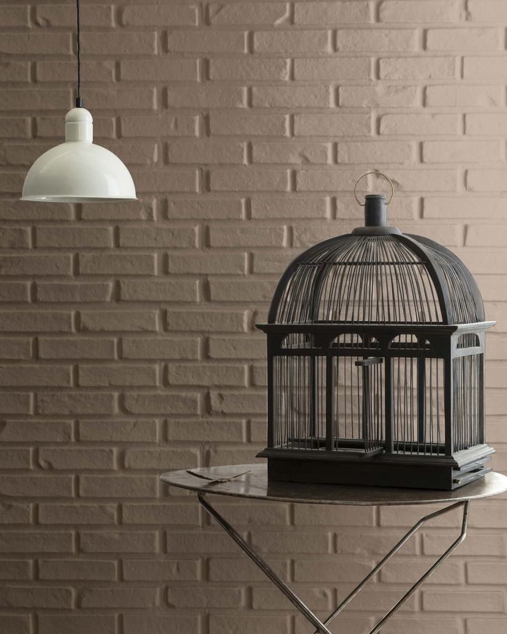 a birdcage sitting on top of a table next to a white light fixture