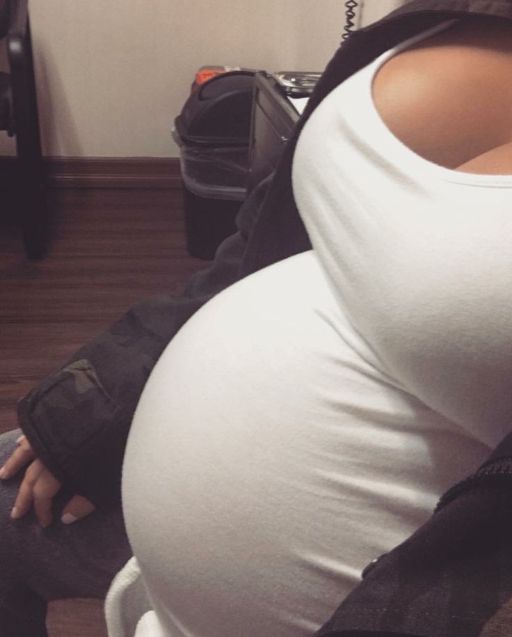 a pregnant woman sitting on top of a white toilet