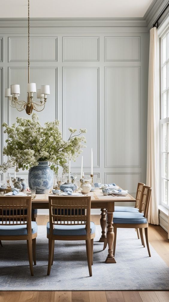 a dining room table with blue chairs and flowers in a vase on the centerpiece