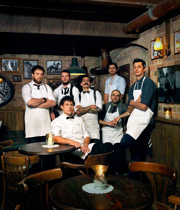 a group of men in aprons are posing for a photo at a restaurant with their arms crossed