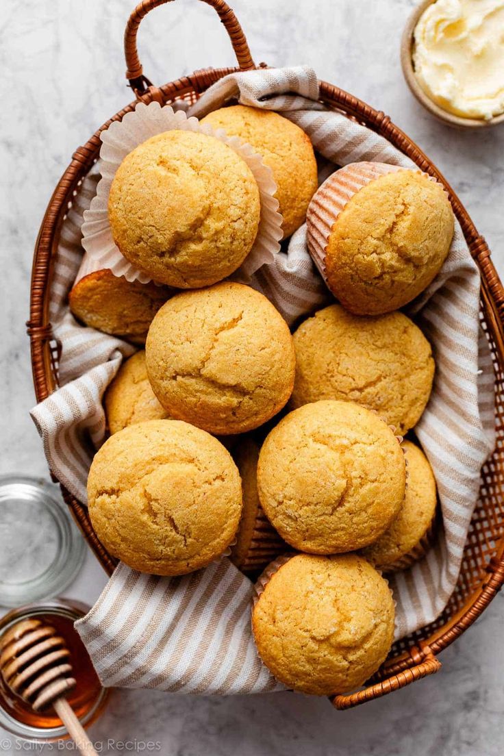 a basket filled with muffins next to a jar of honey