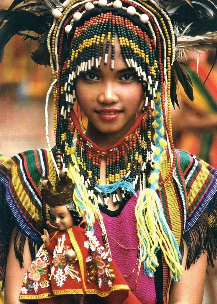 a woman with long braids and headdress holding a doll