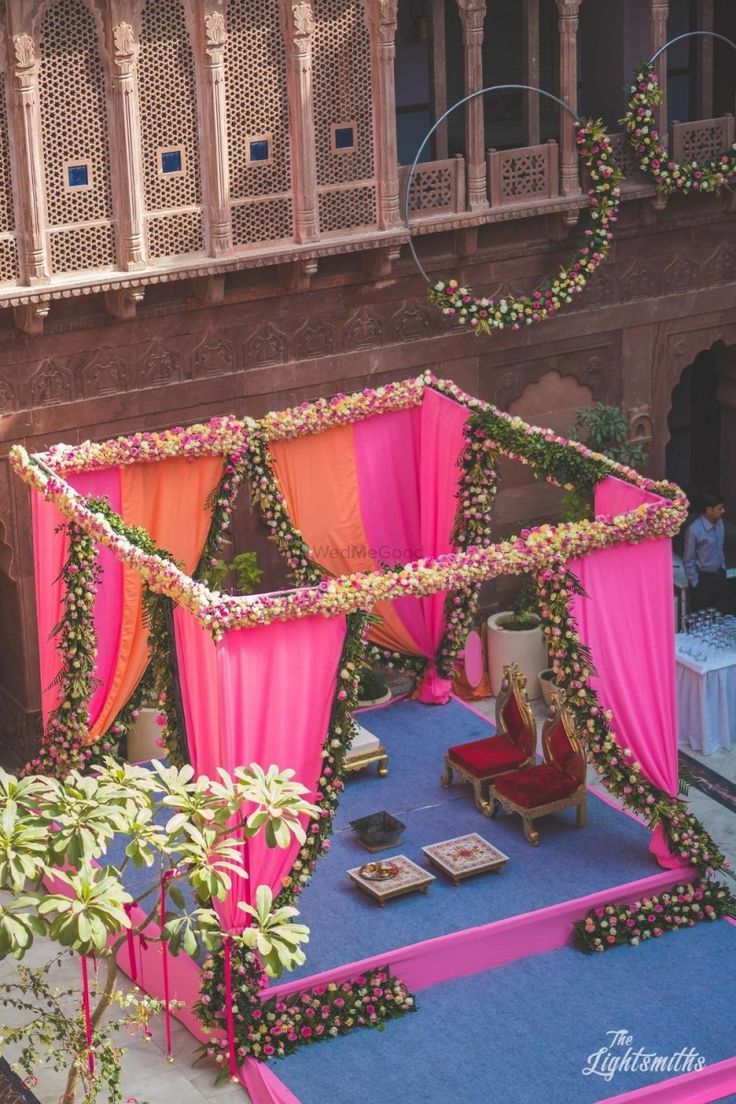 an elaborately decorated stage with pink and orange draping on the sides, surrounded by greenery