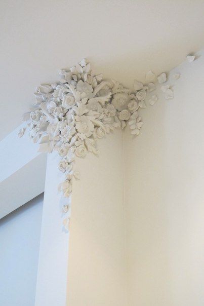 the corner of a room with white flowers on it