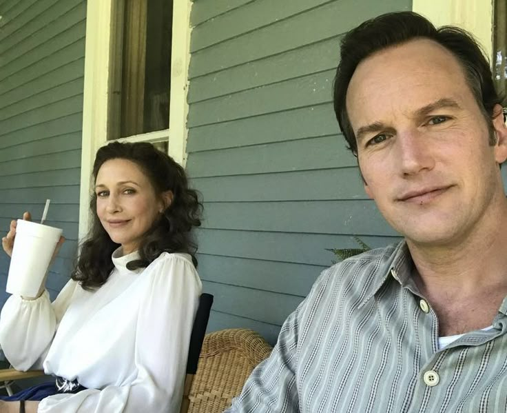 a man and woman sitting on a porch with coffee cups in front of their faces