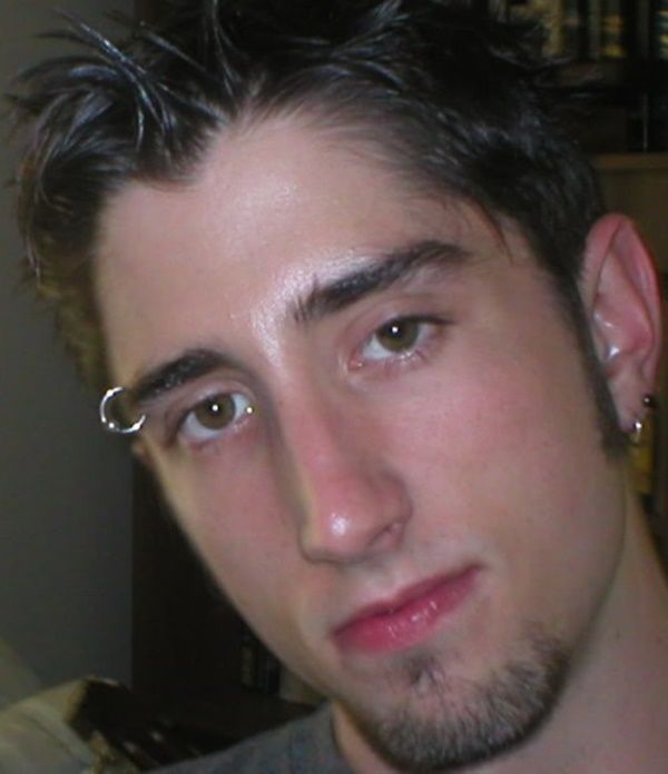 a man with piercings on his ears looking at the camera