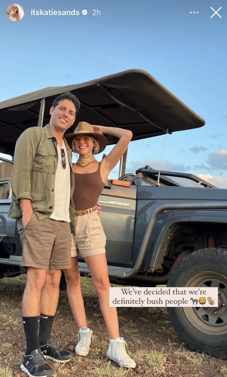 a man and woman standing in front of a truck with an awning over it