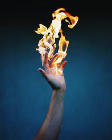 a hand with flames coming out of it's palm is shown in front of a blue background