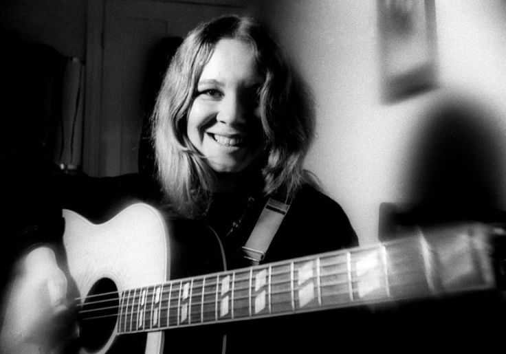 a black and white photo of a woman playing an acoustic guitar