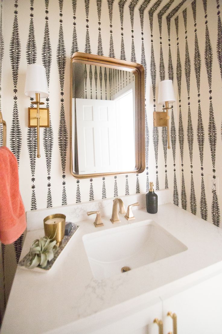 a white sink sitting under a bathroom mirror next to a wall mounted faucet