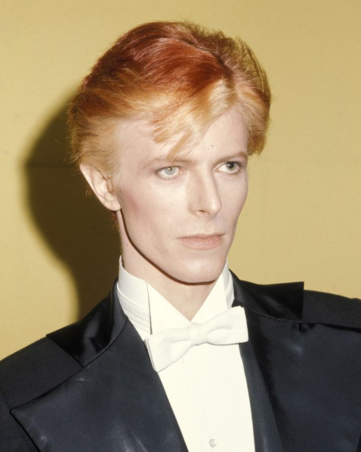 a man in a tuxedo with red hair and blue eyes wearing a white bow tie