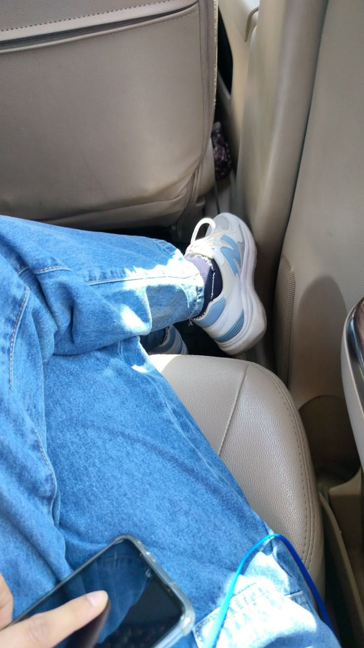 a person sitting in the back seat of a car with their feet on a cell phone