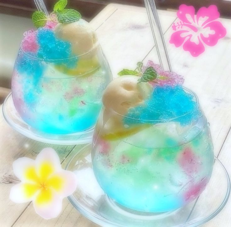 two glasses filled with ice cream and sprinkles on top of a wooden table