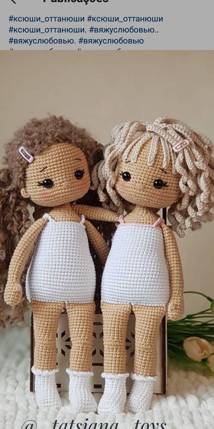 two crocheted dolls sitting next to each other on top of a white blanket