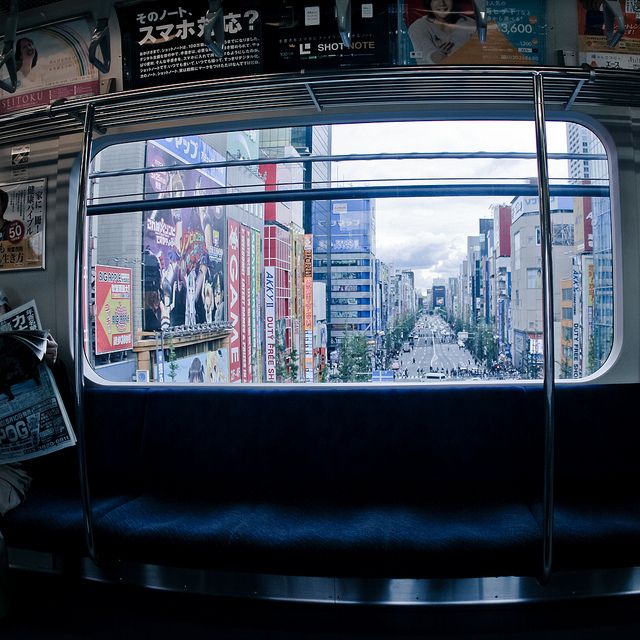 the view from inside a subway car looking at buildings and billboards on the wall