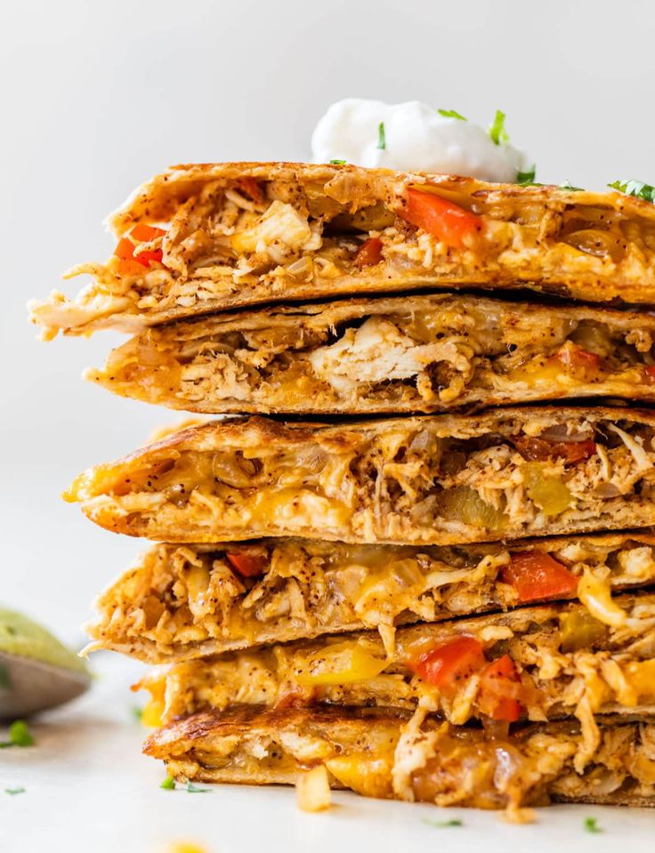 stack of mexican chicken quesadillas with sour cream on top