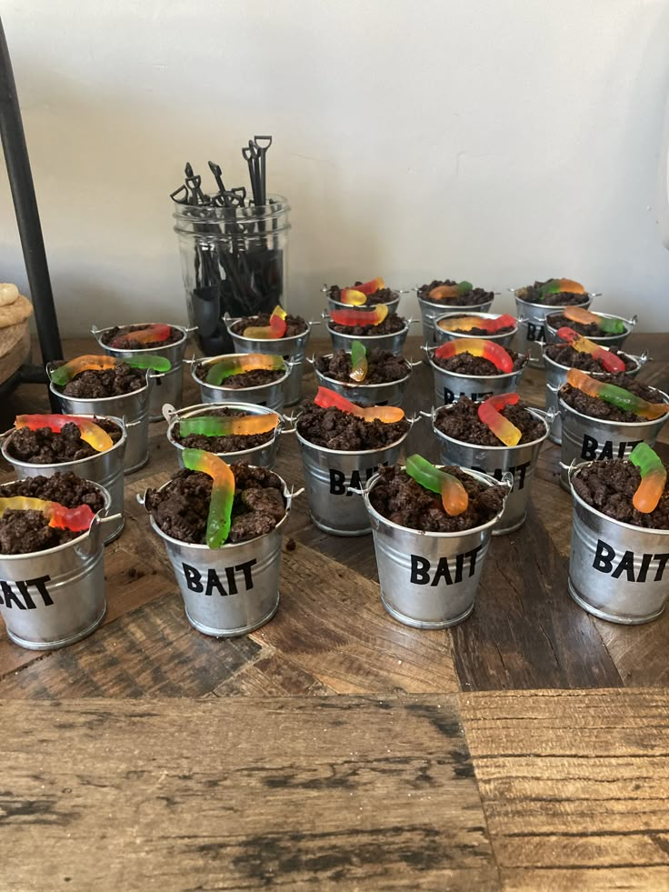 a table topped with metal buckets filled with dirt and candy bars covered in candies