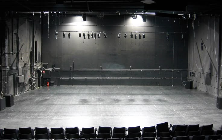 an empty theater with rows of seats and lights on the wall above them, in dark lighting