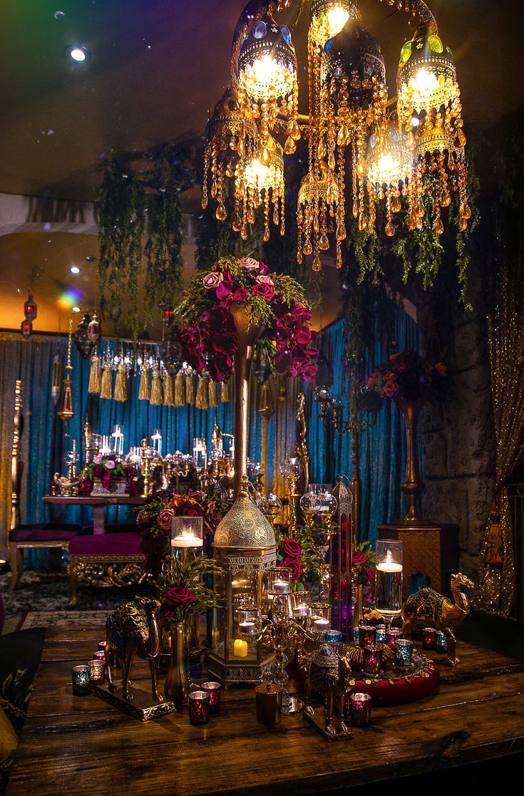 a table topped with lots of vases filled with flowers next to a chandelier