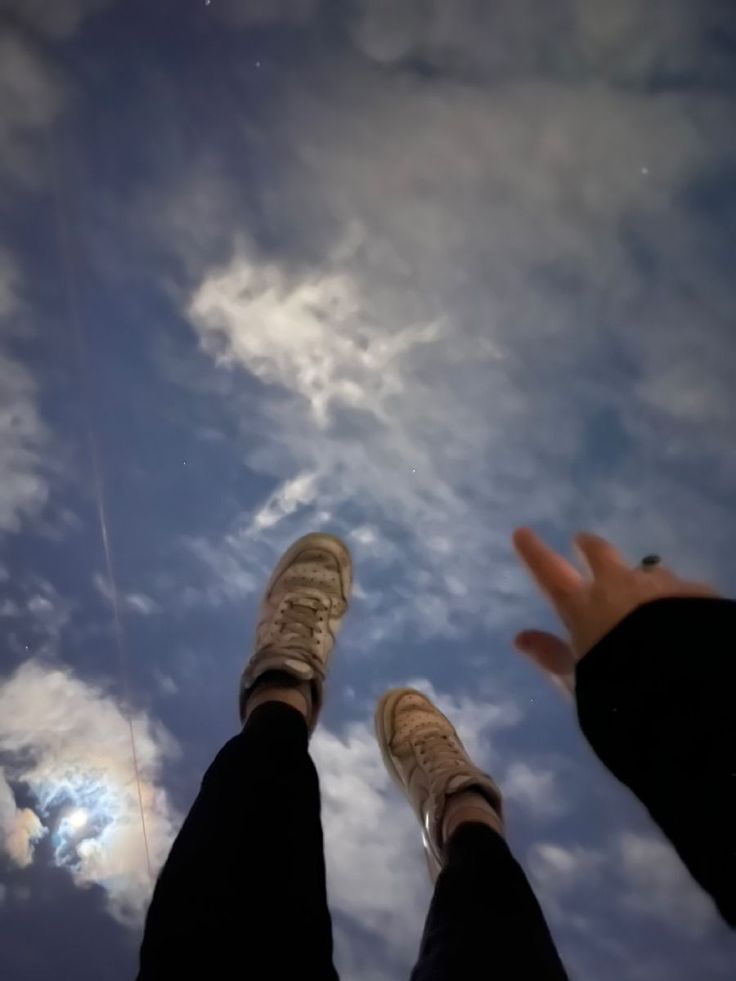 two people standing in the sky with their feet up and one person holding out their hand