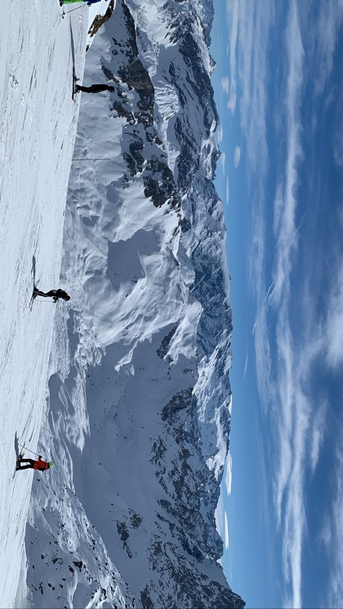 three skiers are skiing down the side of a snowy mountain