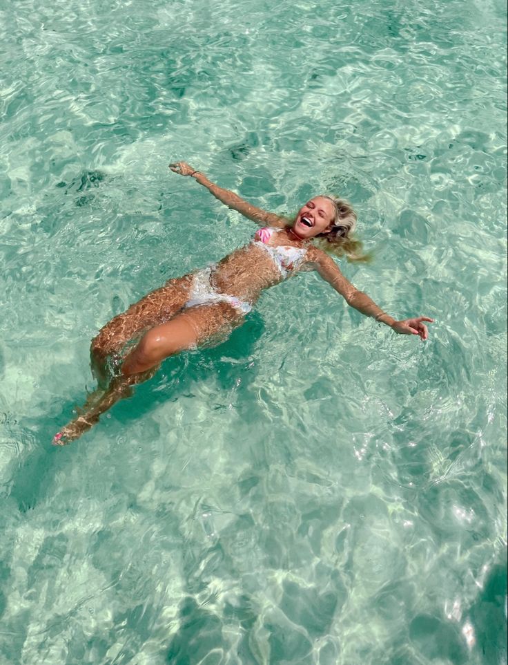 a woman is floating in the clear blue water