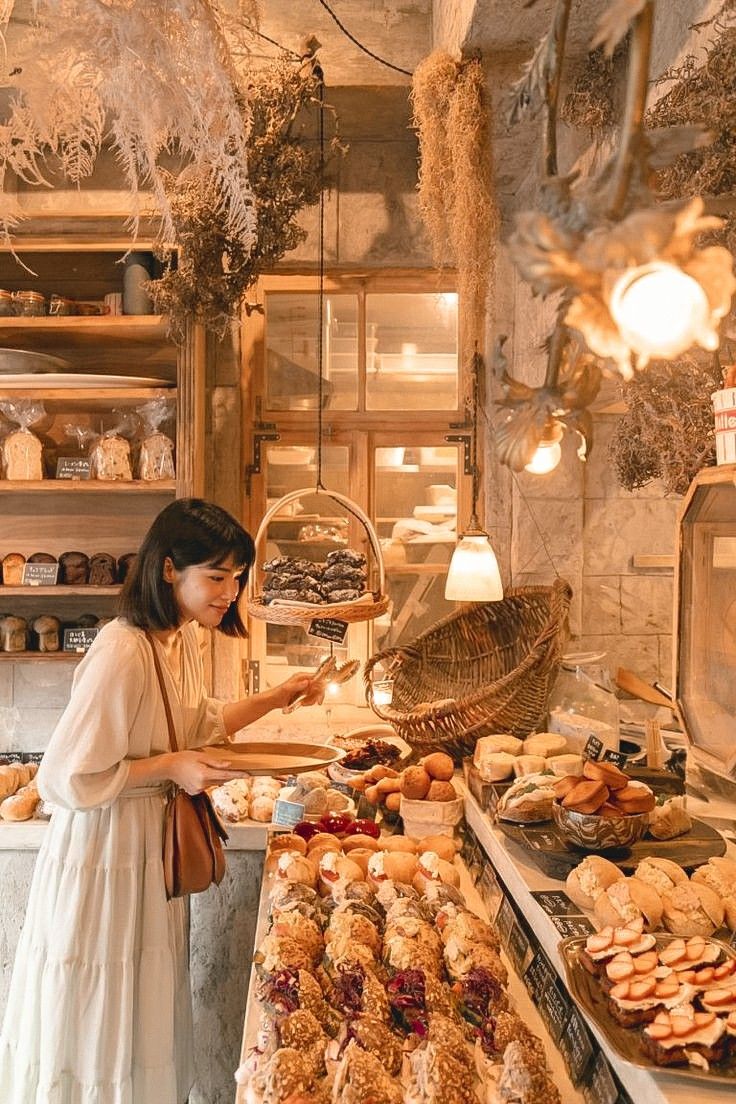 a woman standing in front of a counter filled with pastries