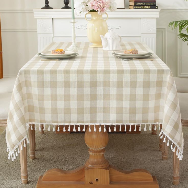 a table with two plates on it and flowers in vases behind the table cloth