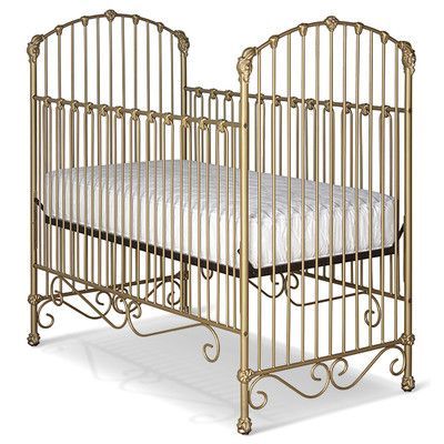 a gold metal crib with a white bed in it