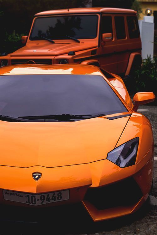 an orange sports car parked next to a red jeep