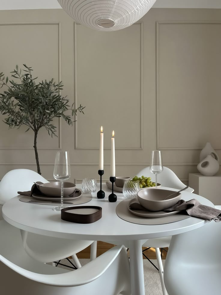 a dining room table set for four with place settings and candles on the side tables