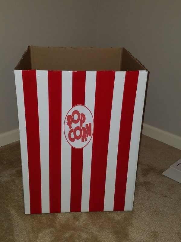 a red and white striped box sitting on top of a carpeted floor next to a wall