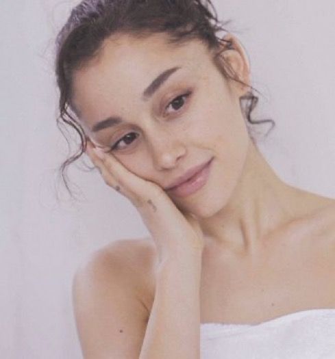 a woman with her hand on her face posing for the camera while wearing a towel