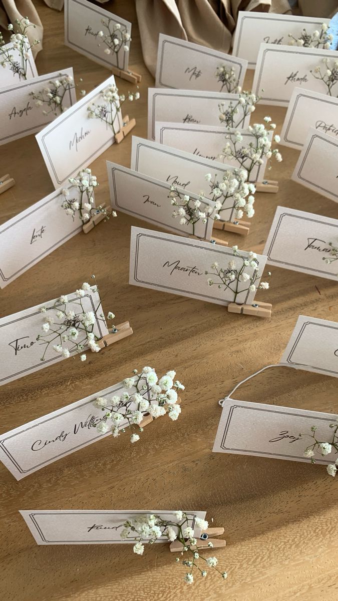 there are many place cards with small flowers on the top and one has a name tag attached to it