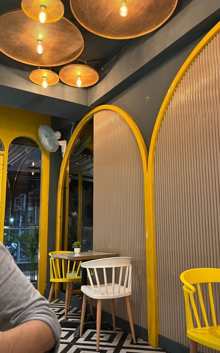 a man sitting at a table in front of yellow chairs