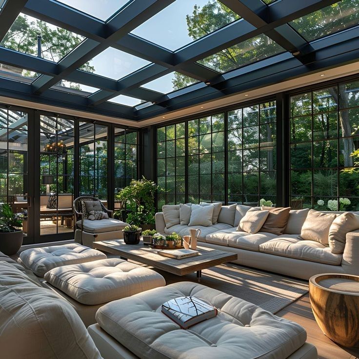 a living room filled with lots of white furniture and large glass windows on the ceiling