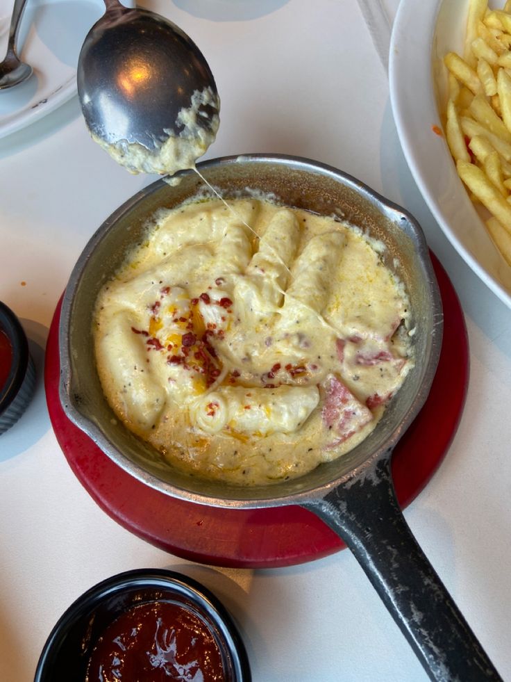 a pan filled with food sitting on top of a table next to bowls of sauce