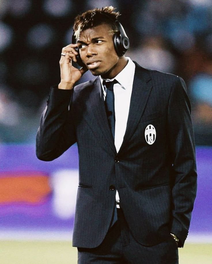 a man in a suit and headphones talking on a cell phone while holding a soccer ball