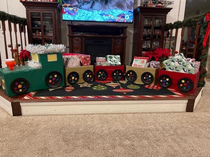 a christmas train with presents sitting on top of it in front of a flat screen tv