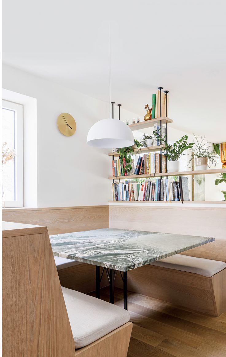 a dining room table and bench with bookshelves in the background