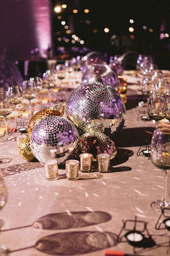 a table topped with lots of shiny disco balls and glasses filled with wineglasses