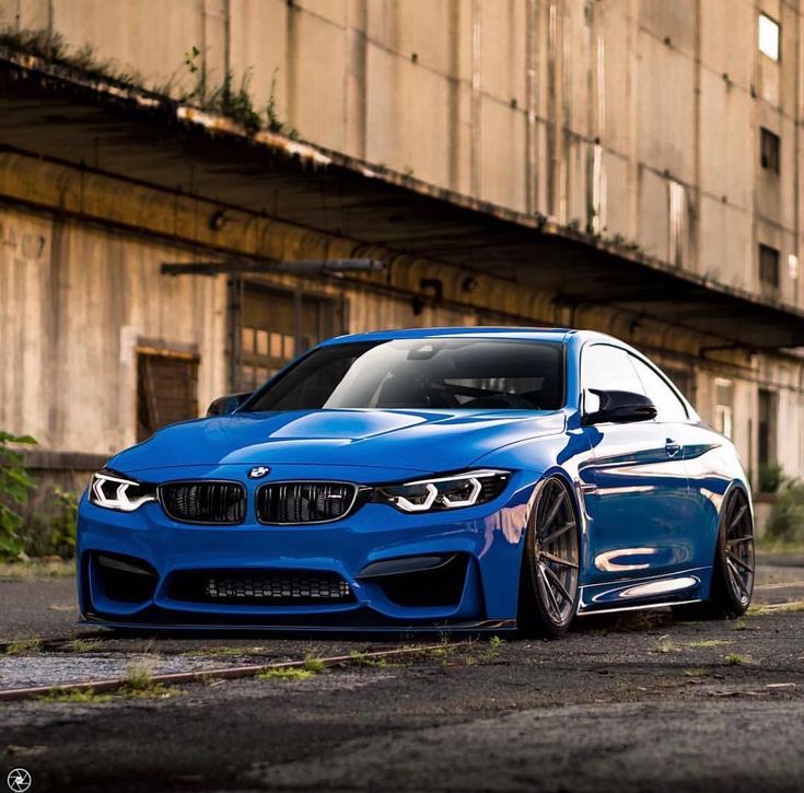 a blue bmw car parked in front of an old building with graffiti on the walls