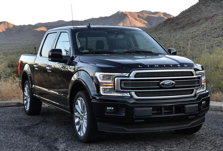 a black truck is parked on the side of the road in front of some mountains