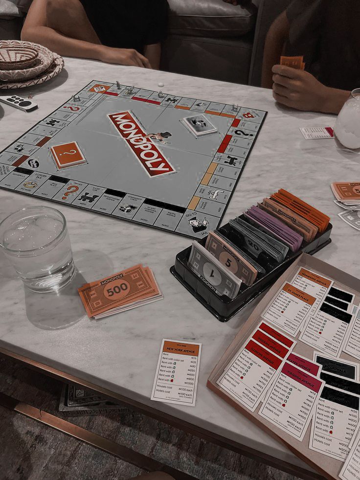 a monopoly board game sitting on top of a table next to two glasses and cups