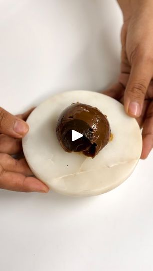 two hands holding an uncooked donut with chocolate icing