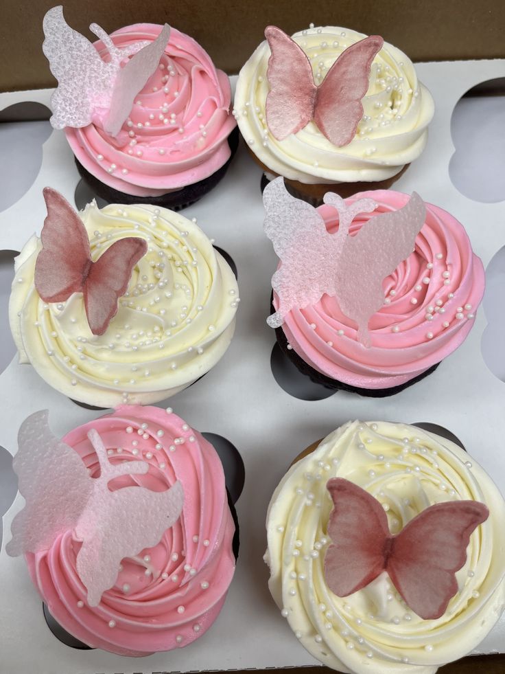 six cupcakes with pink and white frosting in a box