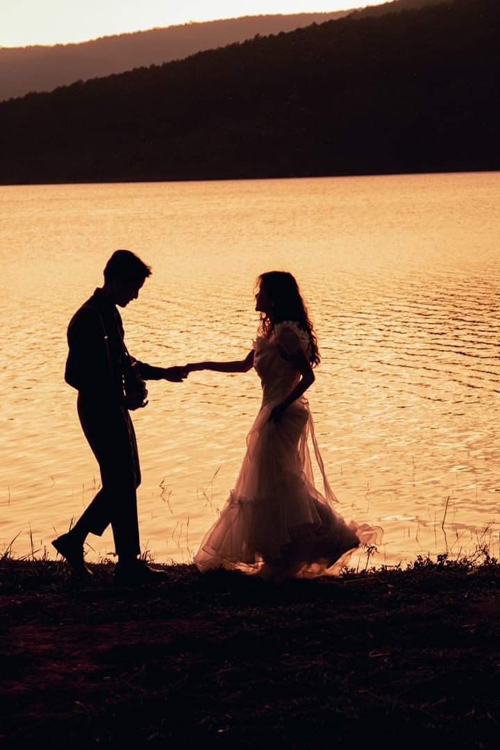 a man and woman standing next to each other near water