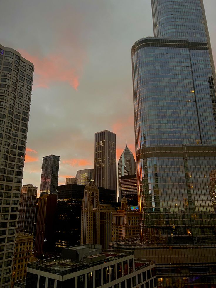 the city skyline is lit up at sunset with skyscrapers in the foreground and clouds in the background