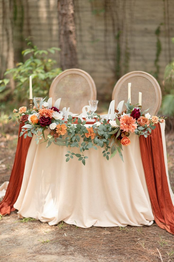 the table is set up with two chairs and flowers on it, along with candles