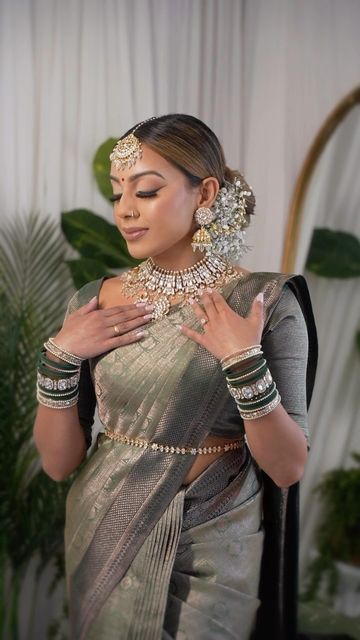 a woman in a silver sari with jewelry on her neck and hands around her chest